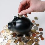 An image of coins beside a piggy bank.